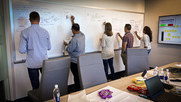 Photo of four professionals sketching ideas on a whiteboard